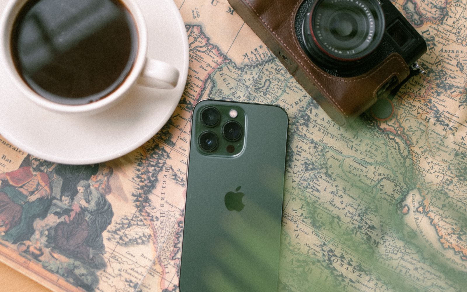 A smartphone, camera, and cup of coffee laid out on a map